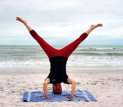 Yoga instructor doing headstand at the beach.