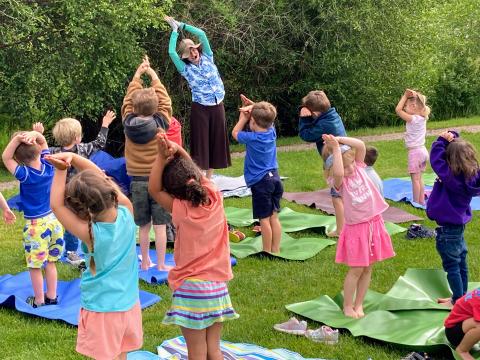 Yoga instructor leading a group of children in a yoga pose.