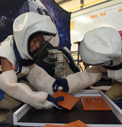 Picture shows two kids dressed as astronauts working together.
