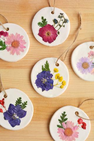 A variety of round, white clay ornaments decorated with colorful pressed flowers