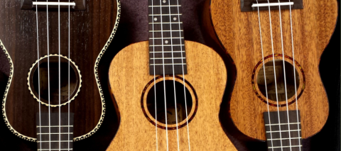 A picture of three wooden ukuleles in various hues